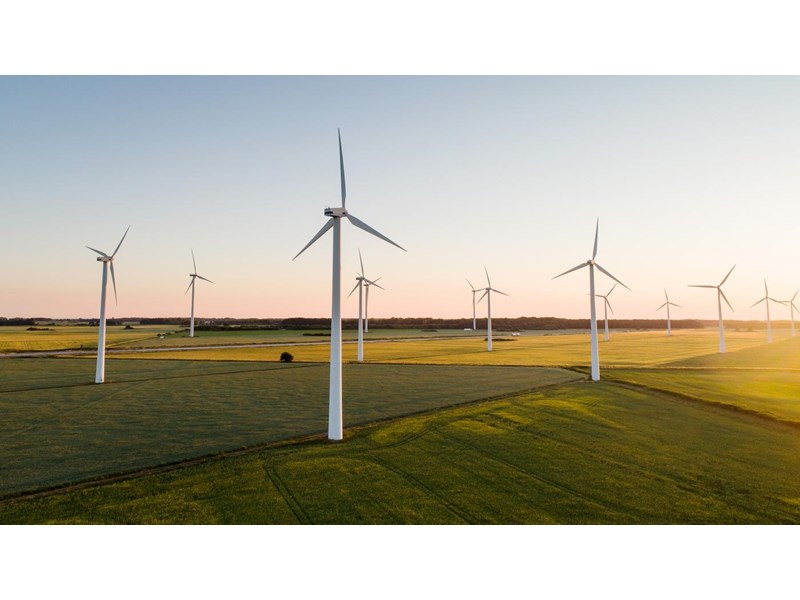 Wind farm in the middle of countryside fields at dusk.